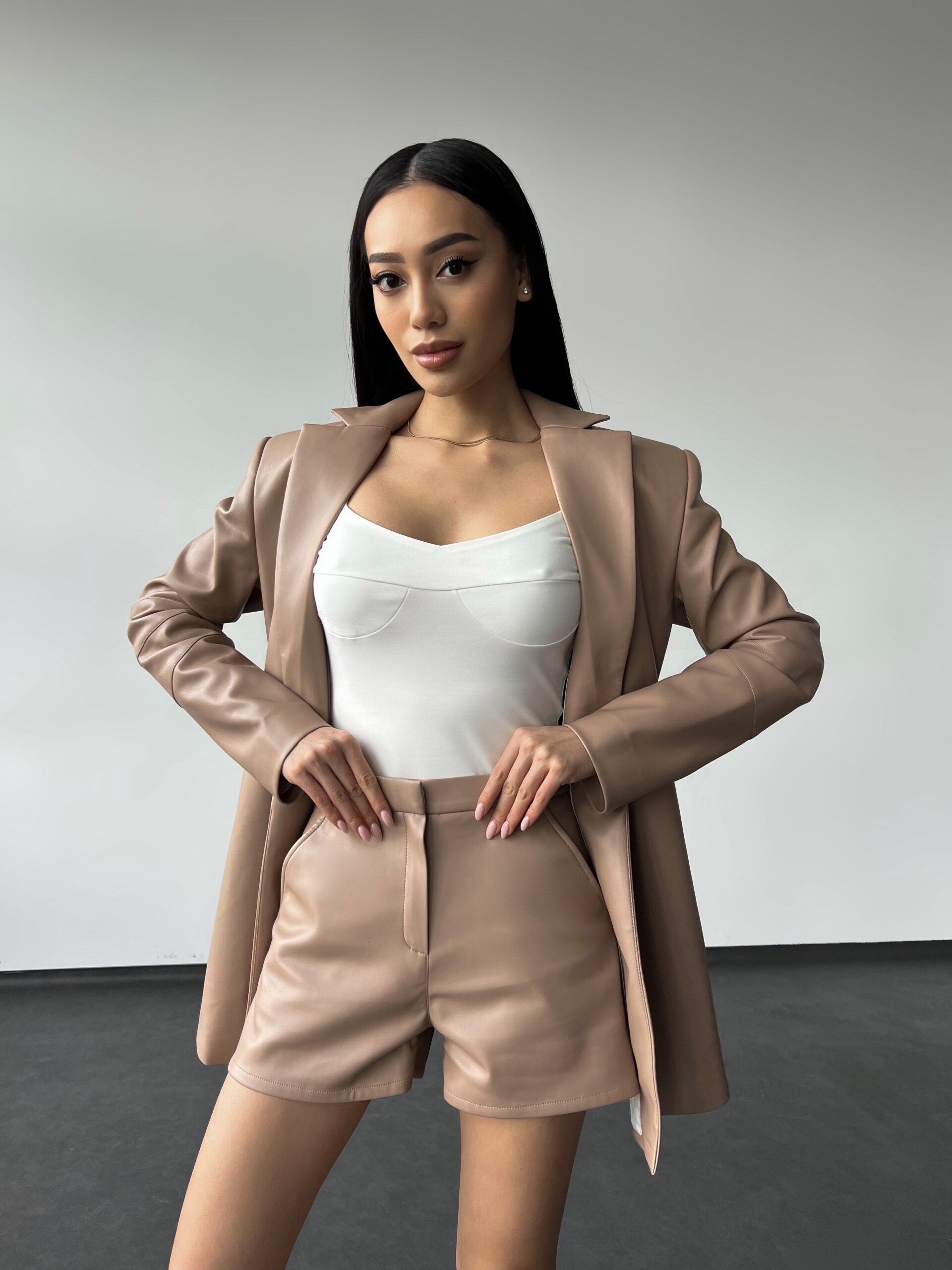 Модель в білому боді та комплекті ECO-LEATHER SUIT від бренду Her Name у кольорі Мокко
