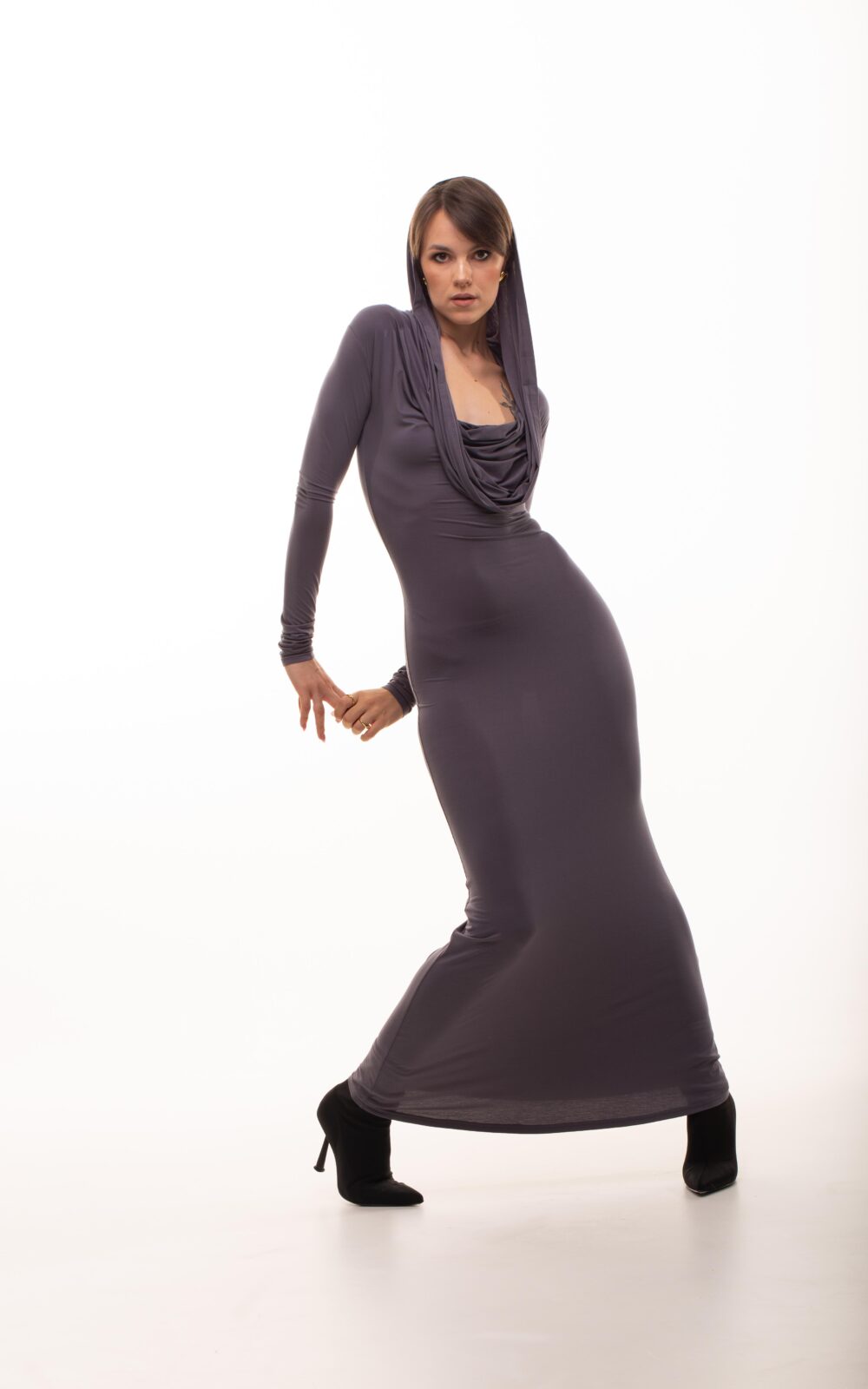 Модель у платті KYLIE MAXI DRESS сірого кольору від бренду Her Name стоїть поклавши руки за спиною