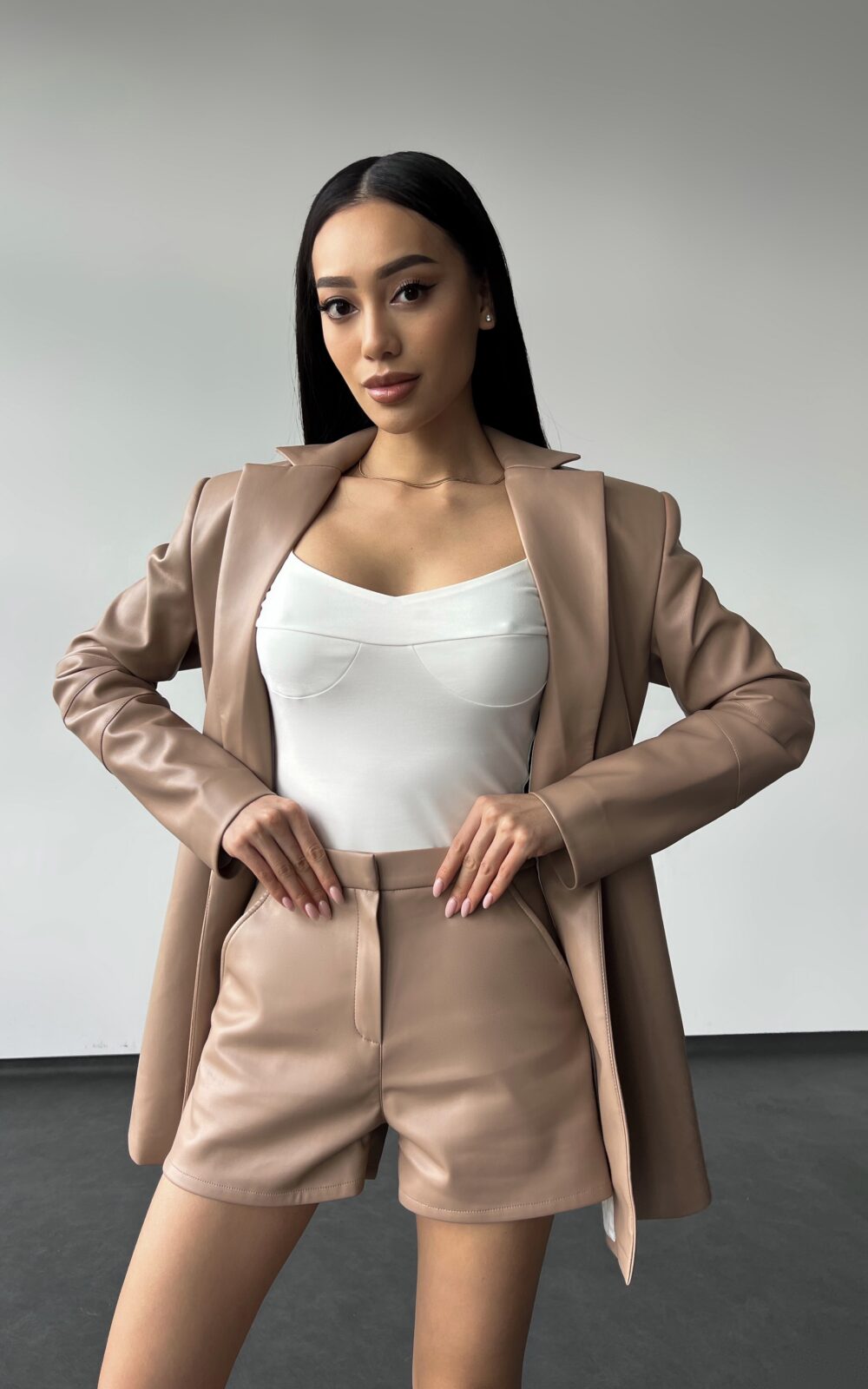 Модель в білому боді та комплекті ECO-LEATHER SUIT від бренду Her Name у кольорі Мокко