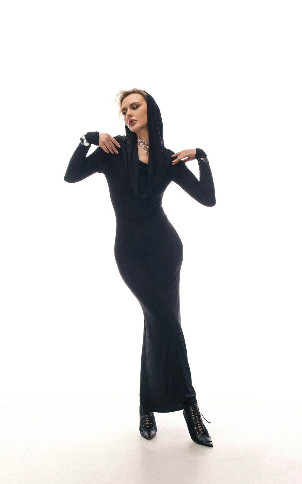Модель у чорному платті KYLIE MAXI DRESS чорного кольору від бренду Her Name стоїть поклавши руки на плечі