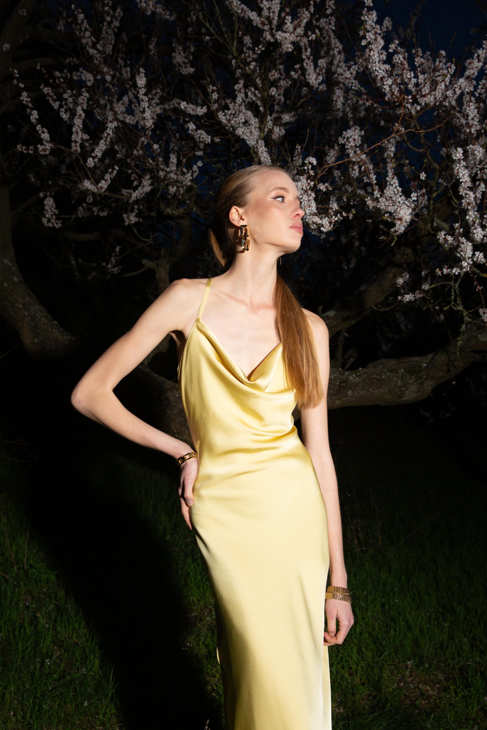 Дівчина у платті лимонного кольору SLIP DRESS “LANA” від бренду Her Name стоїть біля дерева та дивиться в сторону
