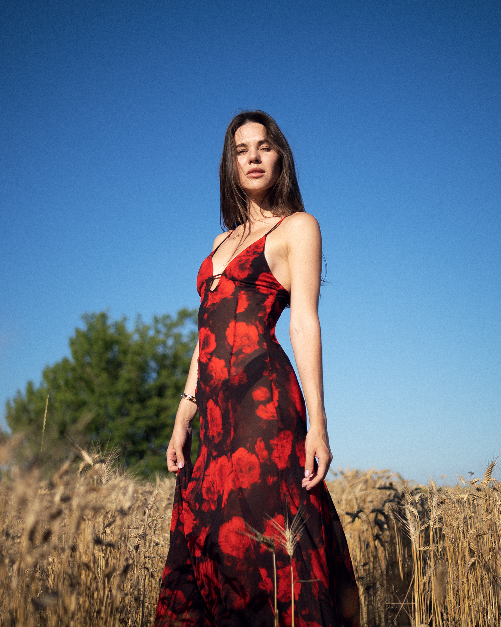 Модель у ANGELINA DRESS (напівпрозорому) платті чорного (Трояндового) кольору від бренду Her Name стоїть боком в колоссях